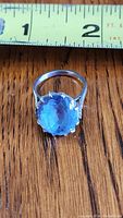 Top view of ring showing oval blue stone and tape measure for scale