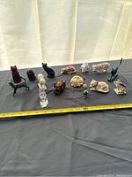 All 14 cat figurines arranged on a black cloth with a measuring tape showing approximately 12 inches across.