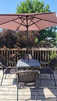 Full view of the patio table with four woven chairs and purple umbrella opened above