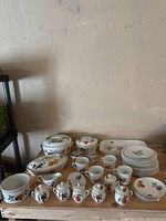 Full view of the full Royal Worcester fruit dinner set arranged on a table showing serving dishes, cups, plates, sugar pots, salt and pepper shakers.