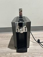 Front view of the Starbucks Verismo espresso machine showing the drip tray, chrome panel with buttons and lever on top.