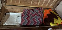 Wooden chest with folded linens, knitted afghans, towels and blankets inside