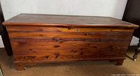 Full frontal view of the cedar chest showing wood grain, hinged lid, and base design.