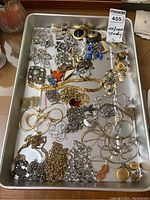 Tray overview showing assortment of rhinestone brooches, pins, earrings, chain necklaces and bracelets