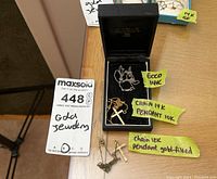 Overview of three necklaces and labels in black jewelry box and on table