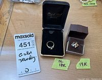 Overall view of both rings in separate display boxes alongside auction card