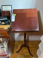 Front view of the wooden music stand showing the clean flat top and polished finish along with the pedestal base and tripod legs.