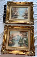 Two small landscape paintings on canvas with ornate gold frames and ruler for scale included.