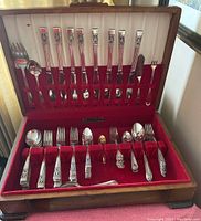 Top view of the full set of Rogers Bros silver plated flatware in red velvet-lined wooden box with white satin lid lining