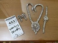 Necklace, bracelet, and earrings alongside auction label 'Sterling jewelry'