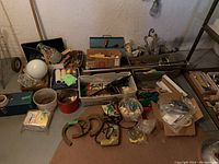 General overview of assorted tools, hardware, paint supplies, and workshop items laid out on the floor.