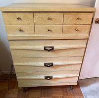 Front view of vintage dresser showing six small drawers with brass knobs on top and four large drawers with metal handles below.
