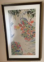 Framed embroidery artwork showing two colorful peacocks with floral background.