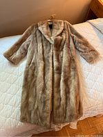 Full front view of vintage Eaton fur coat laid on bed showing length and coat detail.