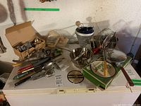 Wide view of the collection showing boxes, mixing bowls, wire mesh fryer basket, and assorted utensils on a freezer.