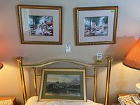 Two framed street scene prints hanging on wall, gold-toned frames with mats