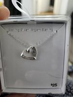 Sterling silver necklace with small open heart pendant displayed on white card, marked $25, new condition