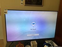 Front view of powered-on 60-inch Samsung television displaying 'No Signal'