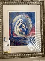 Framed signed and numbered Marc Chagall print depicting figures in blue and white colors, with ornate silver frame. Certificate of authenticity included on back.