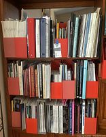 Shelf with red magazine holders filled with books and catalogs on glass art and paperweights