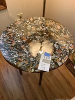 Full view of round table showing painted glass top and four twisted metal legs