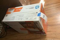 Box standing on side on wooden floor, showing top and side with product labels and branding