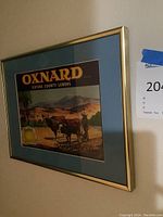 Framed wall art with a vintage-style label for Oxnard Ventura County Lemons featuring cows and a farm landscape.