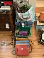 Full view of assortments of handbags, purses, and tote bags arranged on the floor and storage box, showing variety and size.