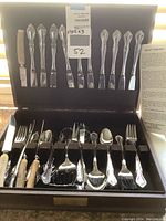 Full view of the flatware set in black case with pamphlet included on the right side.