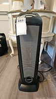 Front view of the Lasko tower fan showing the mesh grille and brand label on base.