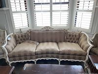 Front view of Louis XV style tufted three-seater sofa with cream and gilded carved wood frame. Upholstered with striped fabric and tufted back.