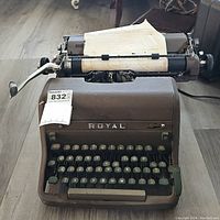Front view of the vintage Royal typewriter showing keyboard, brand name, and paper holder with old paper.