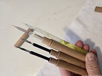 Photo of four all-glass dip pens with pointed nib tips held together, showing details of glass and nibs.