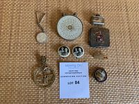 Overview of the lot showing all items including pocket calculator, pins, keychain, helicopter clip, compact tins.