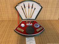 Top view showing all items in fan-shaped green carrying case, five brushes at top, accessories at bottom on red lining