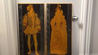 Front view of both carved wood panels side by side showing Victorian man and woman in traditional attire