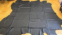 Large spread-out black leather hide showing full size and irregular natural shape.