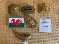 Overview of all six belt buckles arranged on woven mat with auction lot slip
