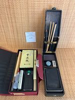 Two calligraphy sets with multiple accessories laid out in cases