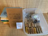 Stack of softcover numismatic journals and British Columbia Pioneer Society Journal volume alongside plastic bin of rolls and loose coins
