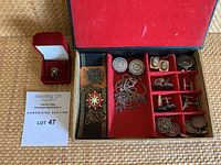 Full view of antique cuff links, pins, and chains organized inside a book-style box with red velvet compartments and a ring in a separate red box.