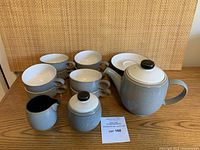 Photo showing teapot, sugar bowl, creamer, and 4 cups with saucers stacked