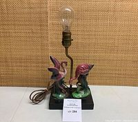 Front view showing lamp on rectangular base with two flamingo figurines and exposed socket