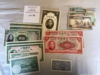 Paper currency bills including multiple denominations from Central Bank of China and a Korean banknote.