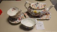 Full view of teapot on platter, sugar bowl, cups and saucers on table