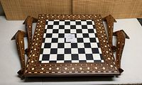 Overhead view of square chess table top showing black and white squares and floral inlay border