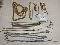 Multiple gold-tone and silver-tone chains and jewelry findings laid out on table showing variety in size and style