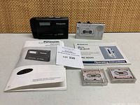 Panasonic RQ-S35V Walkman, Sanyo Micro Talk-Book TRC 6000 recorder, two cassette tapes, and original manuals arranged on surface