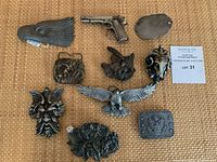 Overview shot of eleven distinct pewter belt buckles on woven background