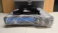 Photo showing portable gas stove still wrapped in plastic packaging with visible control panel and burner grate.